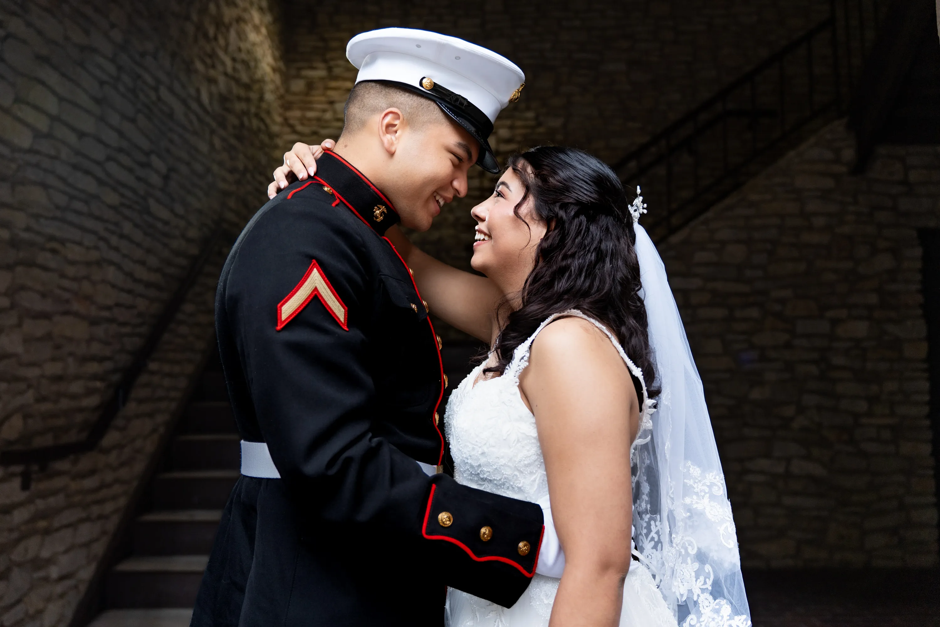 Novio marine con uniforme de gala y su novia nariz con nariz junto a una escalera de piedra en el Mandalay Canal de Irving, Texas