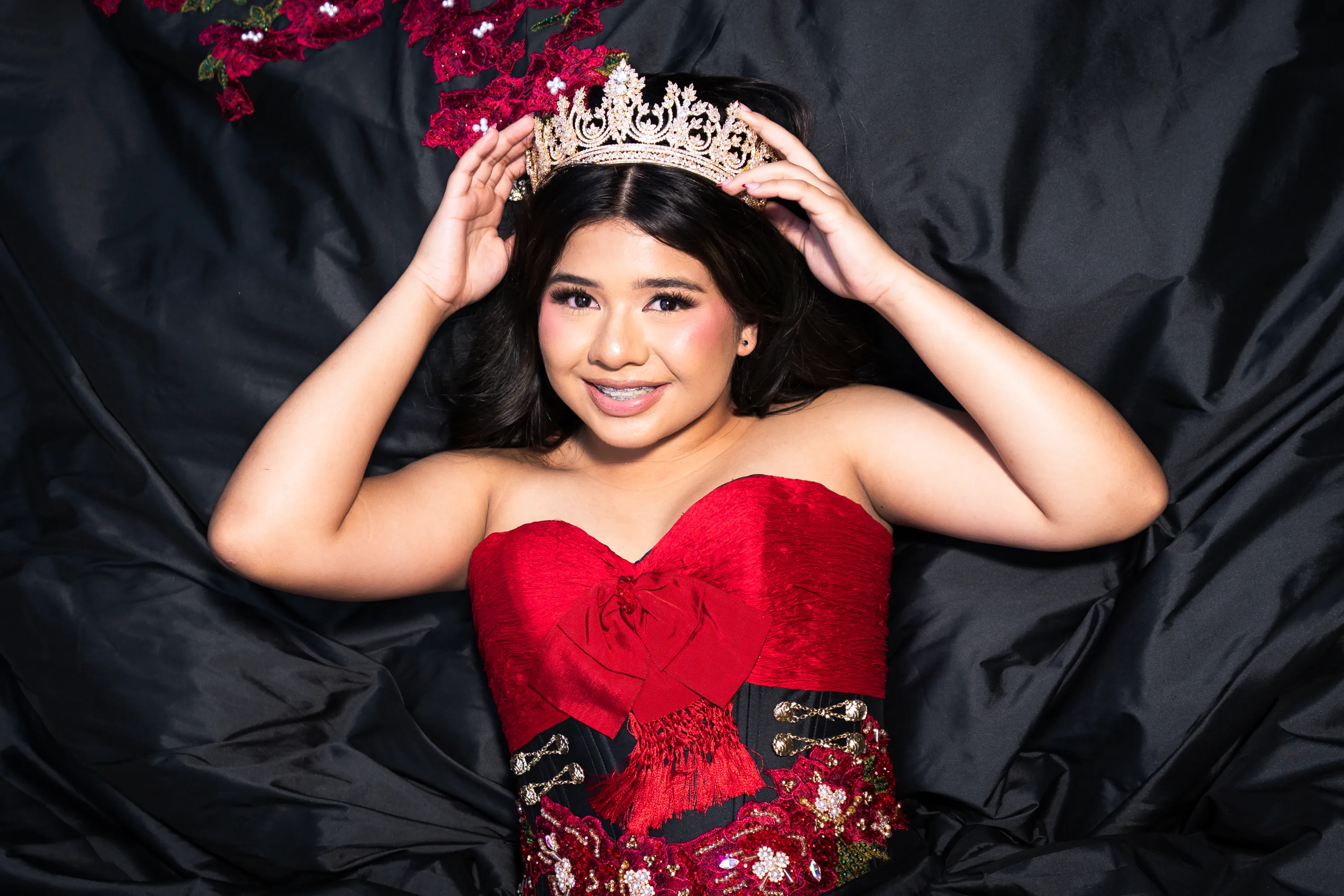 Quinceañera in a black and red charro dress with roses placing her gold crown at the Mandalay Canal in Irving, Texas