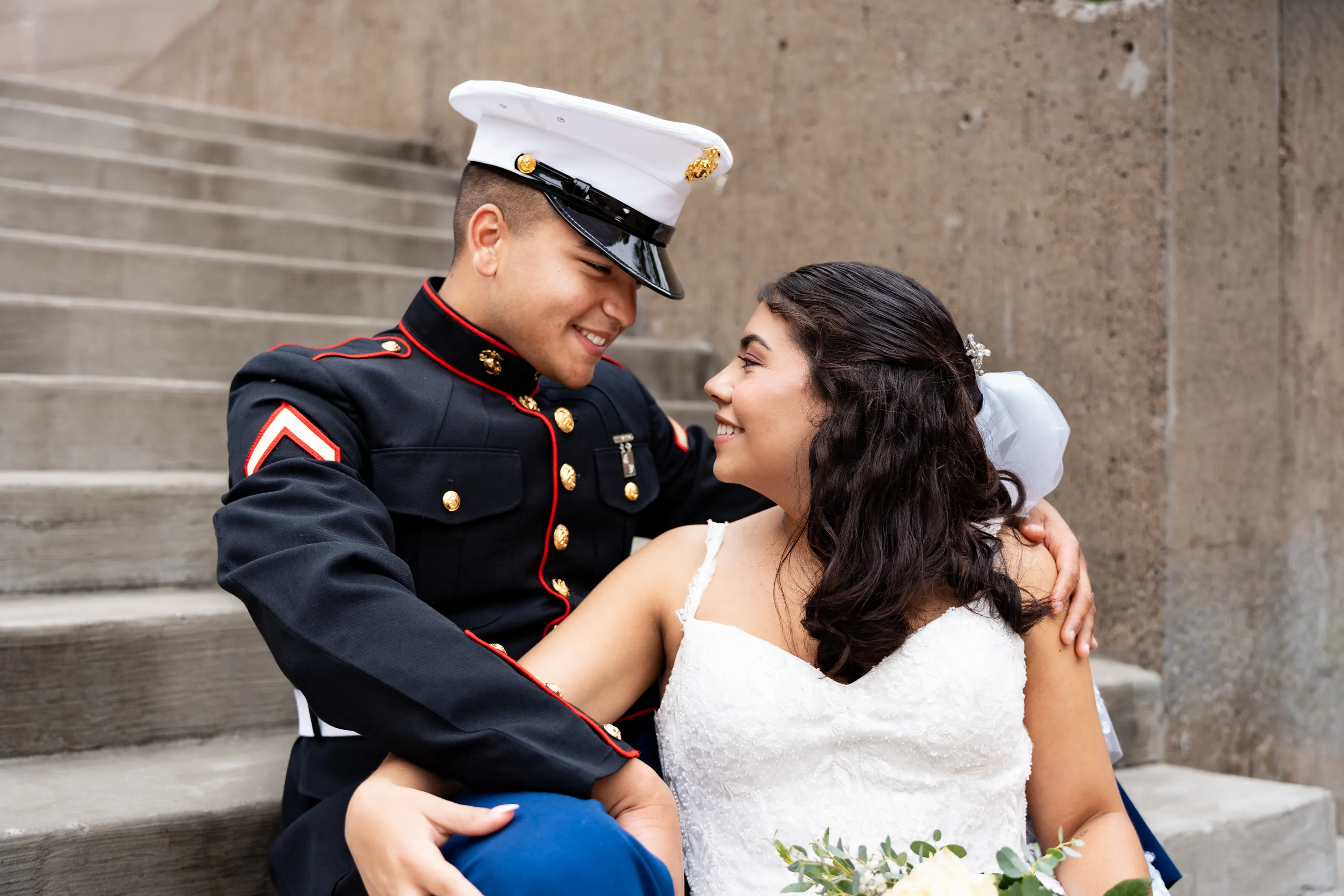 Novio marine y su novia sentados juntos en unos escalones de piedra en el Mandalay Canal de Irving, Texas
