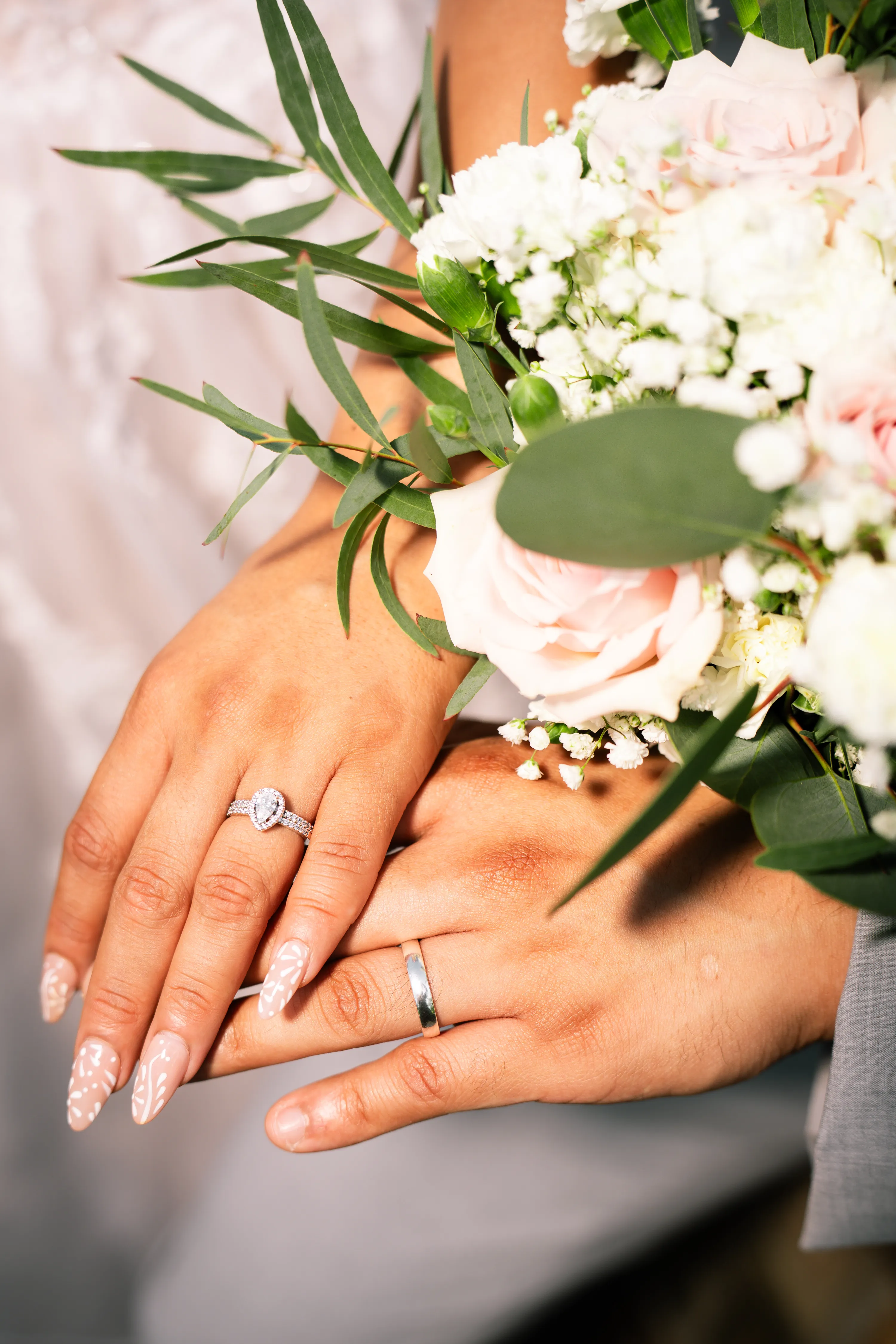 Primer plano de los anillos de boda de los novios y un ramo de rosas rosadas en Turtle Creek Park en Dallas