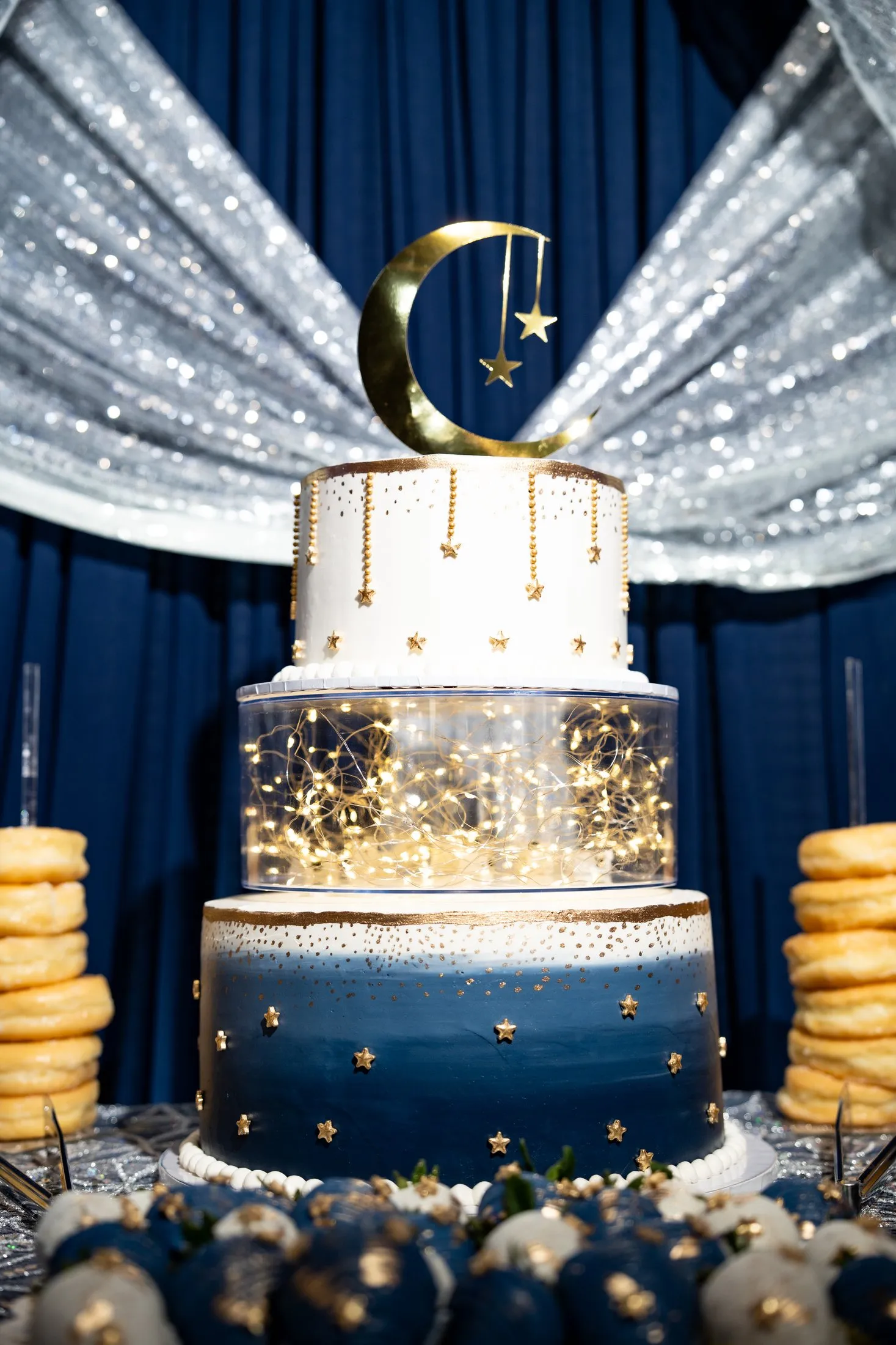 Three-tier celestial quinceañera cake with a gold moon, stars and fairy lights