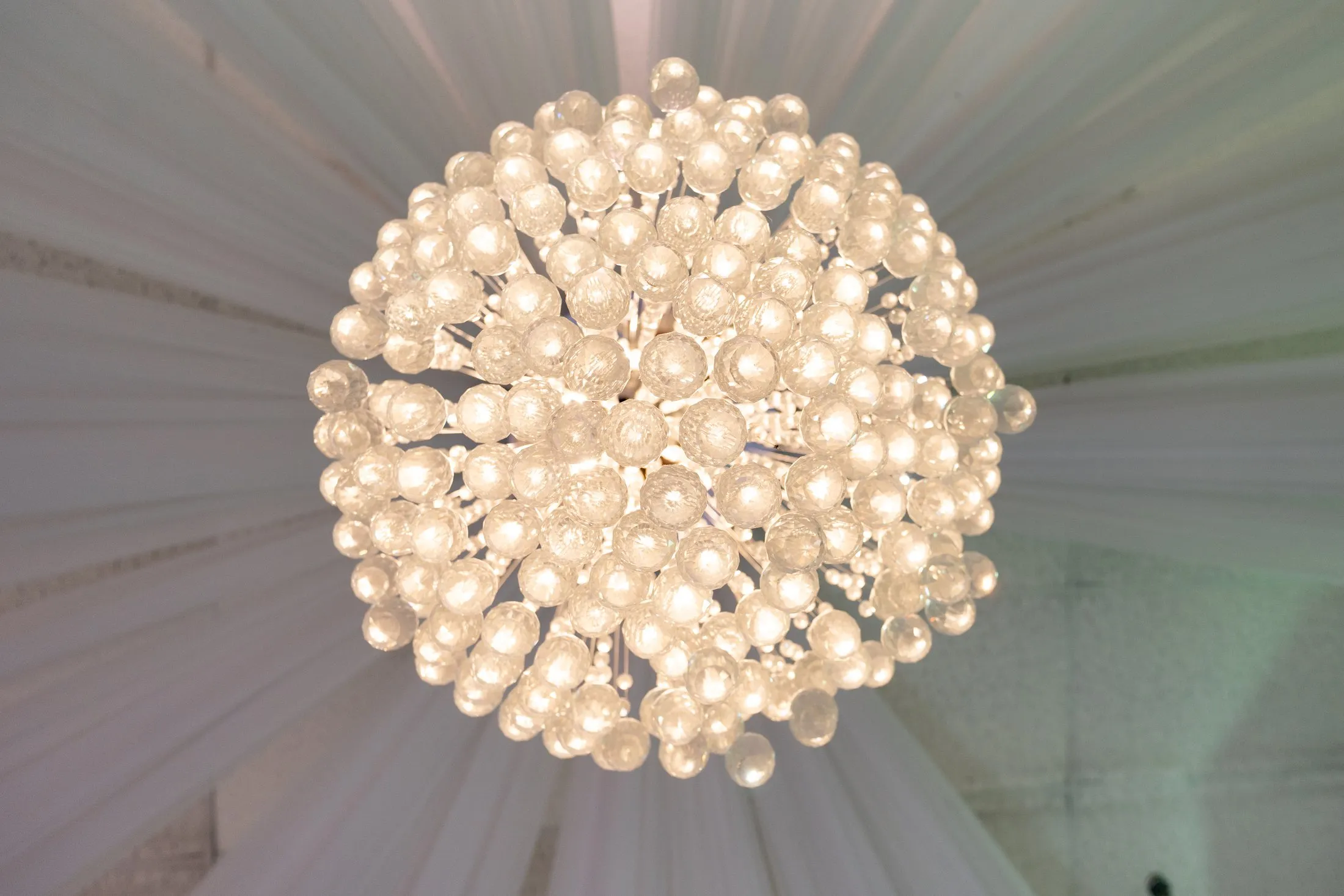 Crystal ball chandelier framed by white ceiling draping