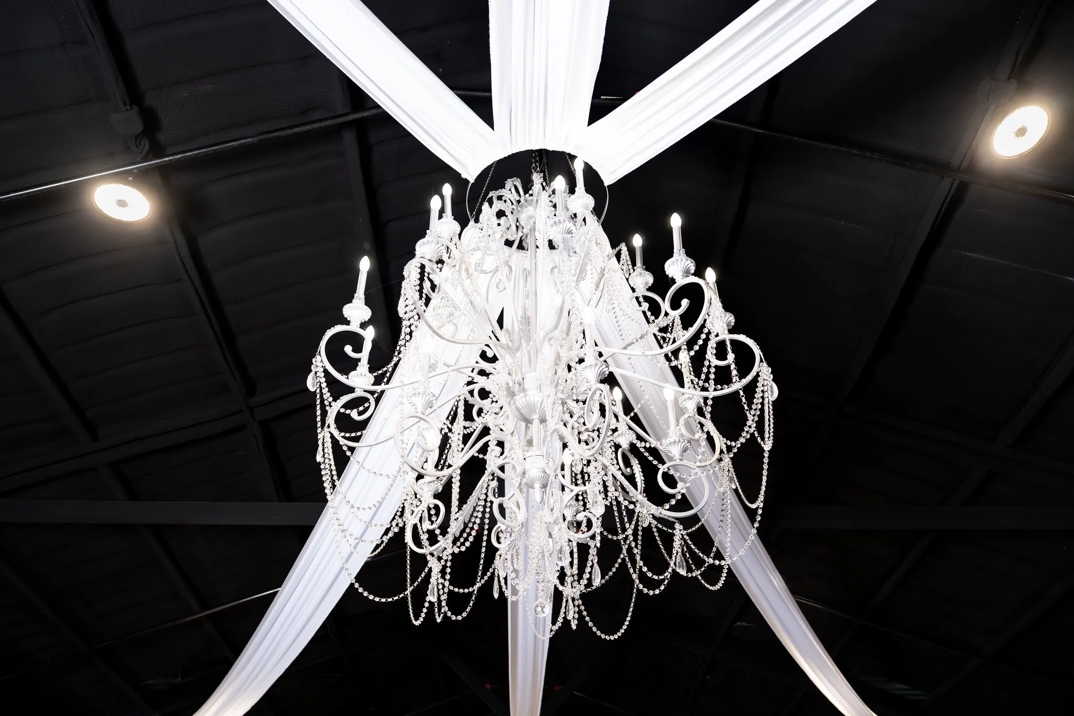 Crystal chandelier with white ceiling draping over the quinceañera reception