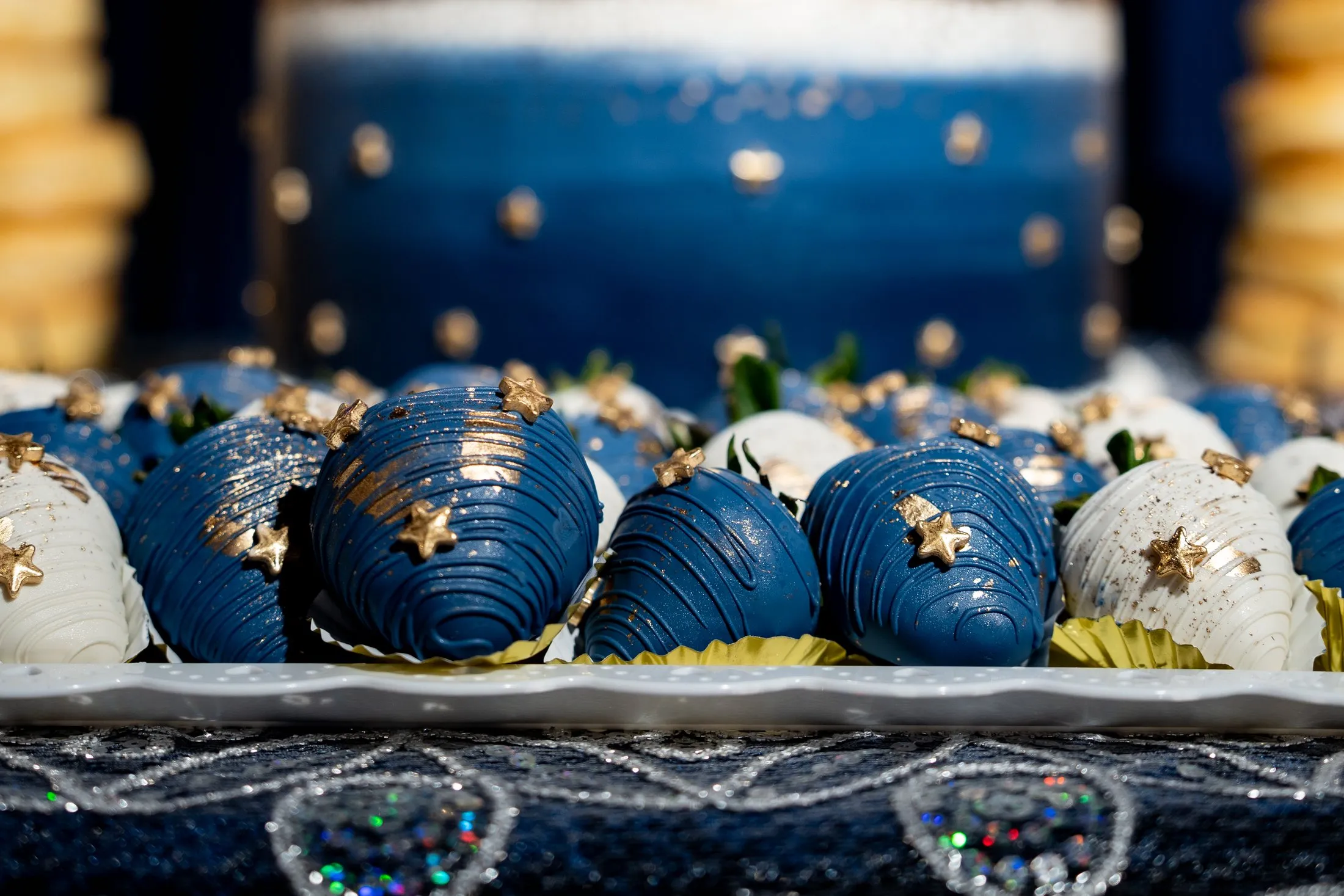 Navy and white chocolate-covered strawberries with gold stars on the dessert table