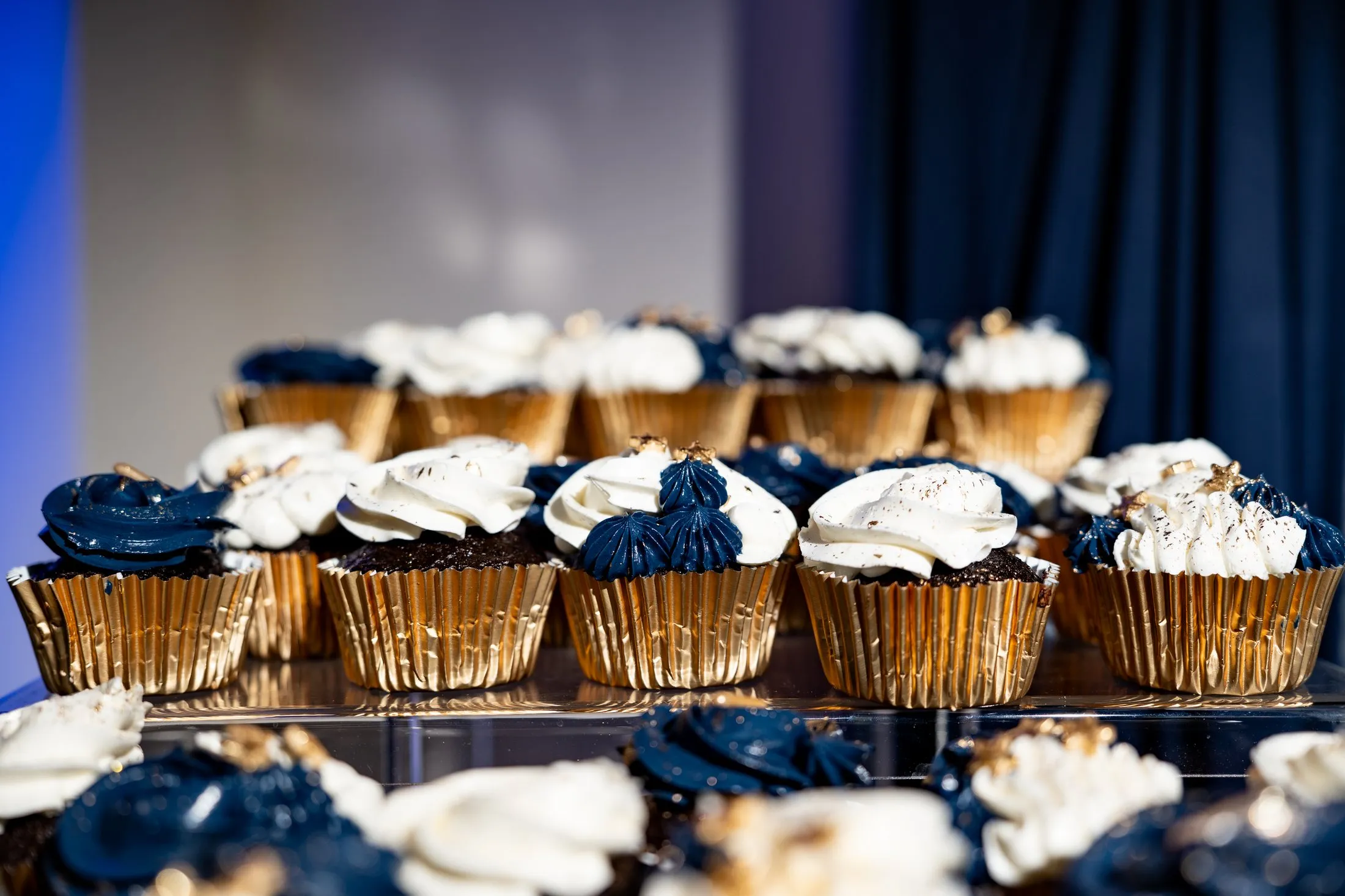 Navy and white frosted cupcakes in gold wrappers