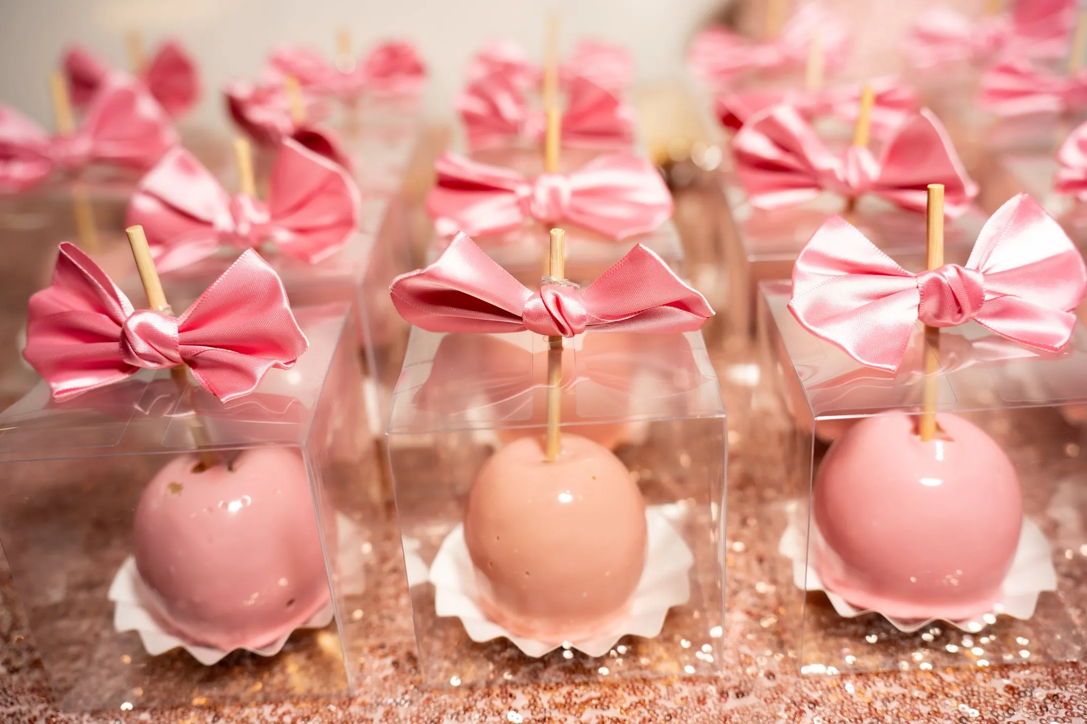 Pink candy apples with satin bows on the quinceañera dessert table at Hidden Acres Ranch in Hudson Oaks