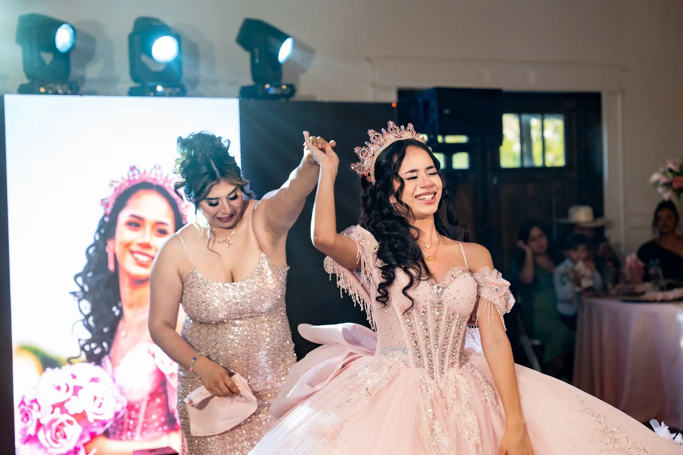 Quinceañera dancing with a dama in front of her photo display at Hidden Acres Ranch in Hudson Oaks