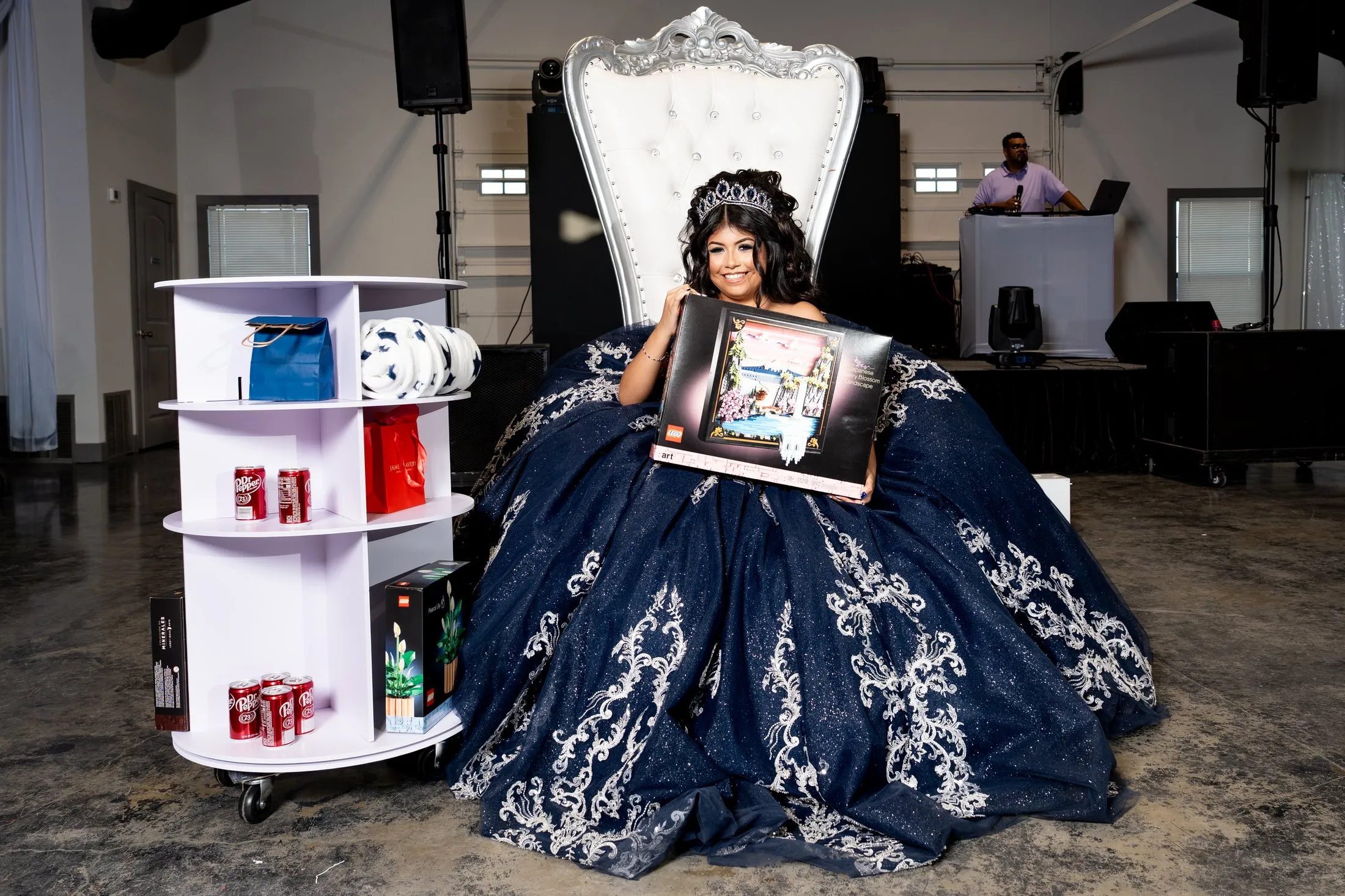 Quinceañera on her throne holding a framed gift during the traditions