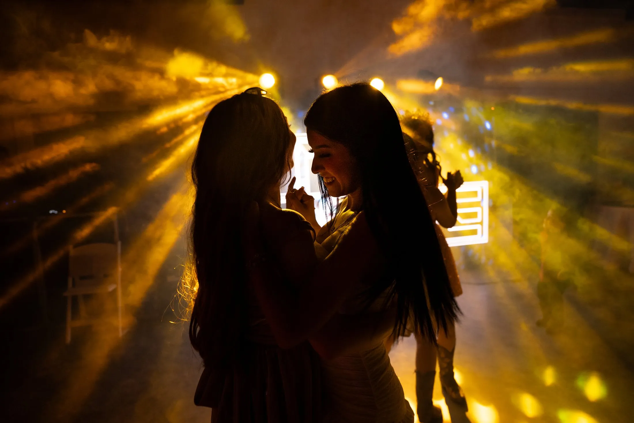 Silhouettes dancing under golden lights at the end of the night at Hidden Acres Ranch in Hudson Oaks