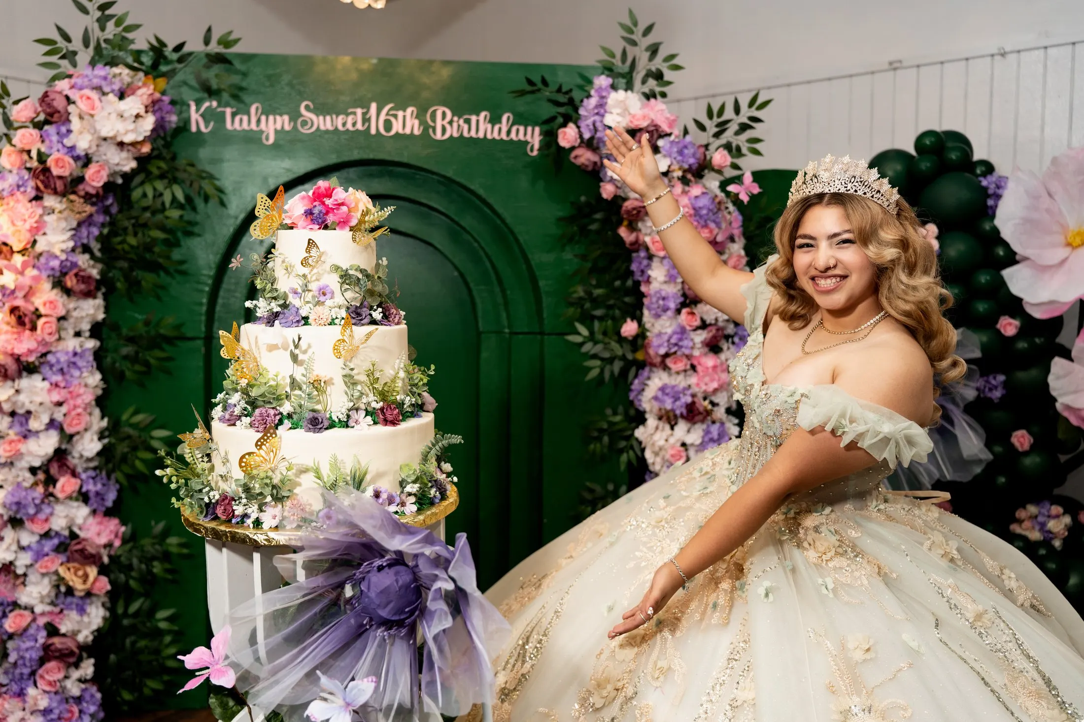 K’talyn celebrating beside her garden cake and green arch backdrop